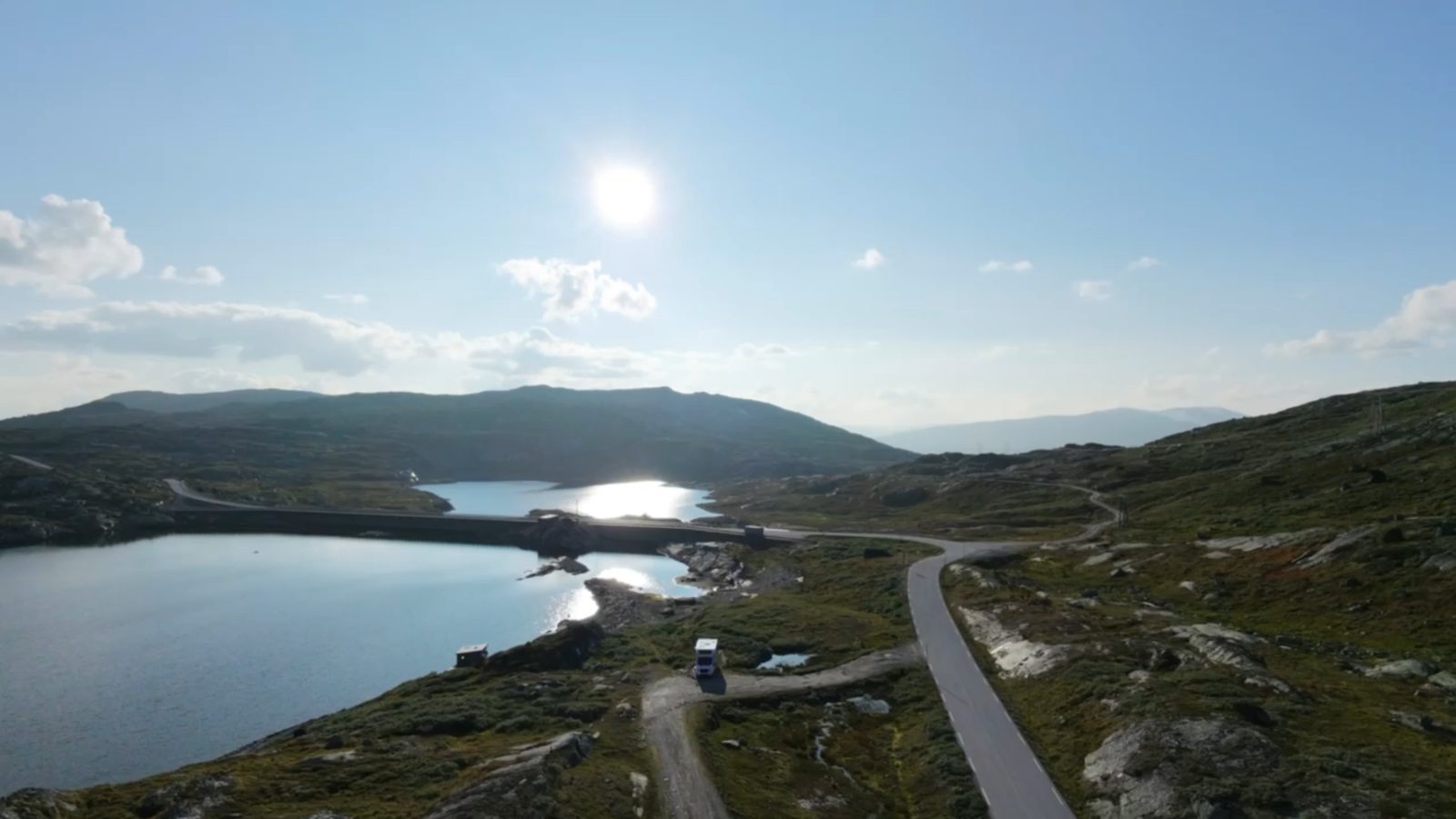 Flygfoto över en sjö och en väg i fjällandskap, taget med drönare